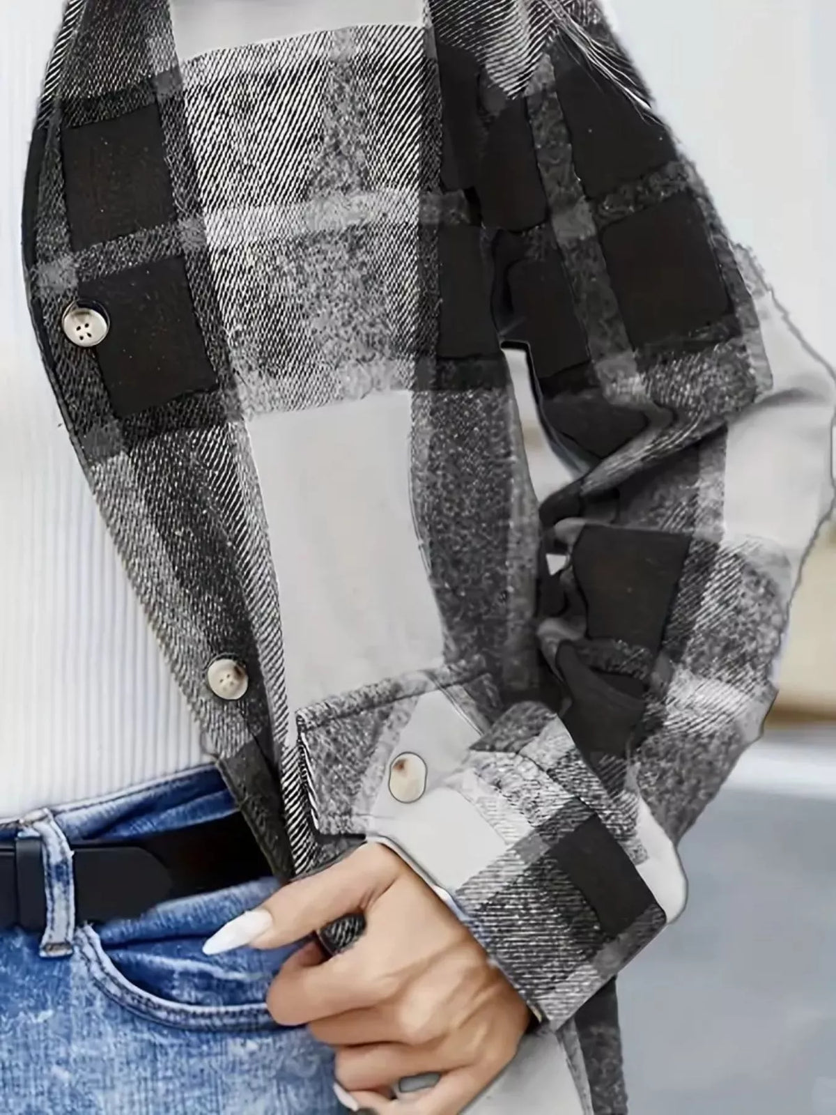 Detalle de sobrecamisa de cuadros negros, grises y blancos para mujer, con manga larga, puño abotonado y tejido de cuadros. NINA AURA COLLECTION.