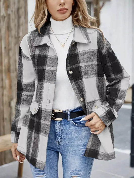 Mujer con sobrecamisa de cuadros negros, grises y blancos, cuello camisero, cierre de botones y bolsillos delanteros, combinada con jersey blanco y vaqueros.